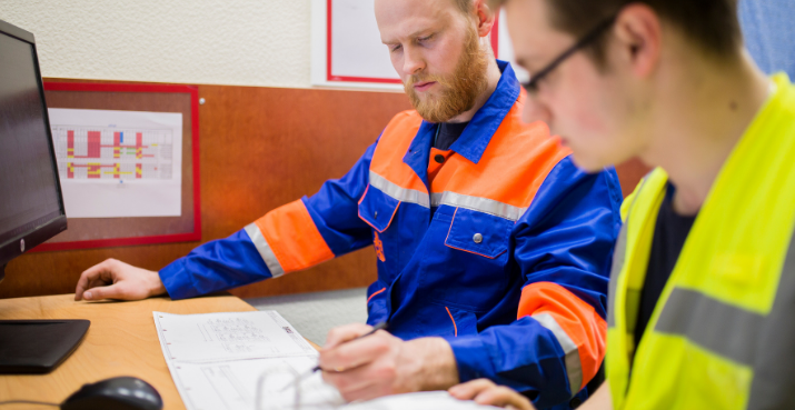 Two men in working gear checking information