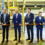 Four men cutting a ribbon in front of a machine in honor of the ceremonial opening of the "Betulin Lab"