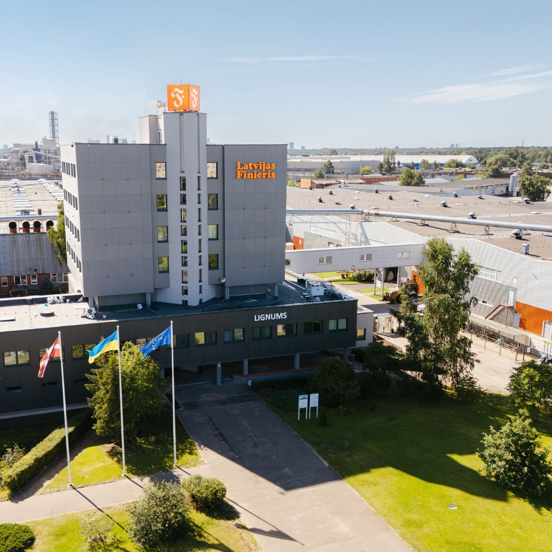 Large plywood mill "Lignums" with a river and other building behind it from bird's-eye view