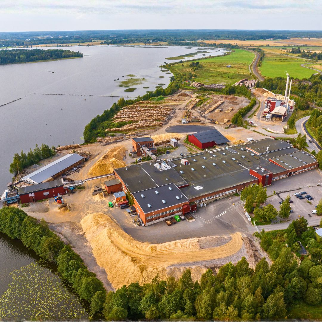 Fniera rūpnīcas "Sastamala" eksterjers, kuras priekšā ir ūdenstilpne un apkārt pilsēta ar kokiem