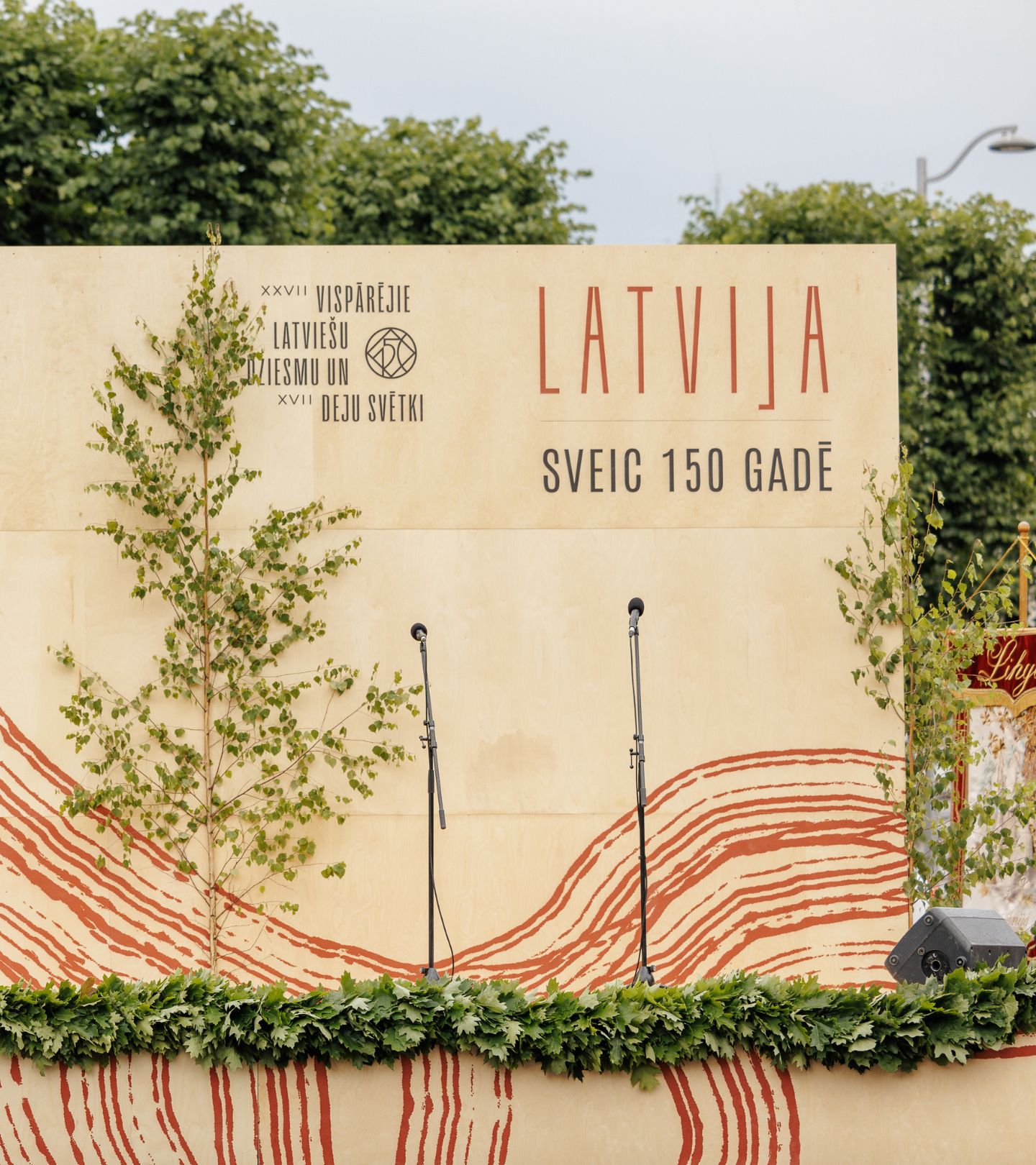A stage with microphones made from plywood decorated with birch trees and oak leaves