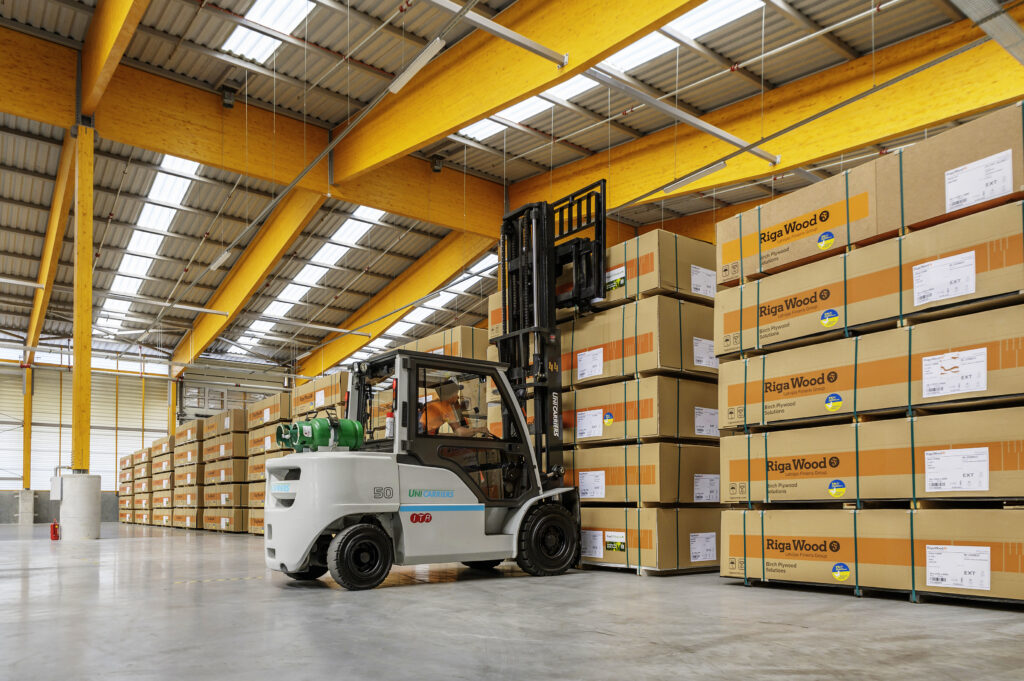 Forklift lifting plywood package with "Riga Wood" logo on it