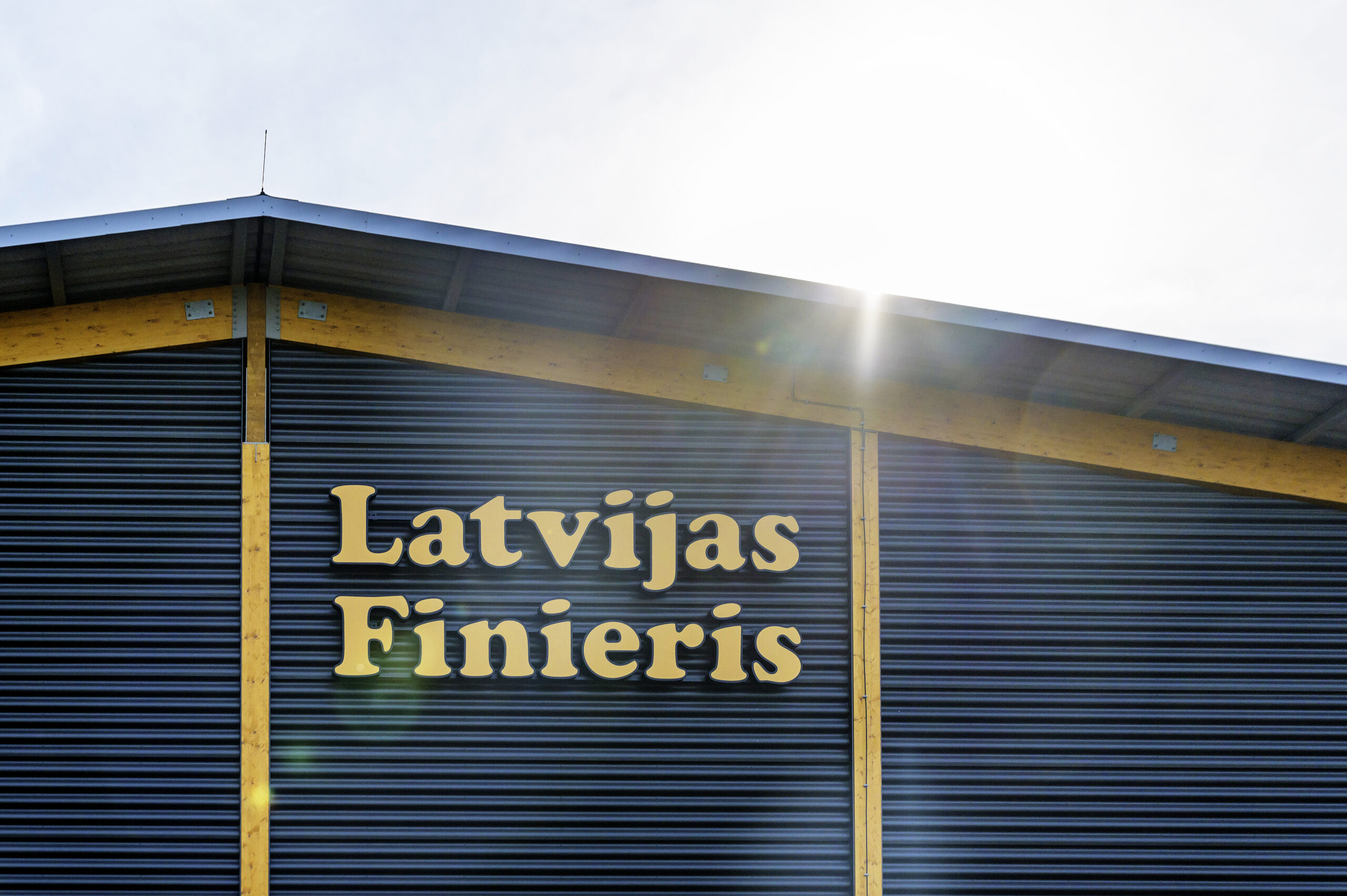 "Latvijas Finieris" logo on the front of a modern warehouse with wooden elements