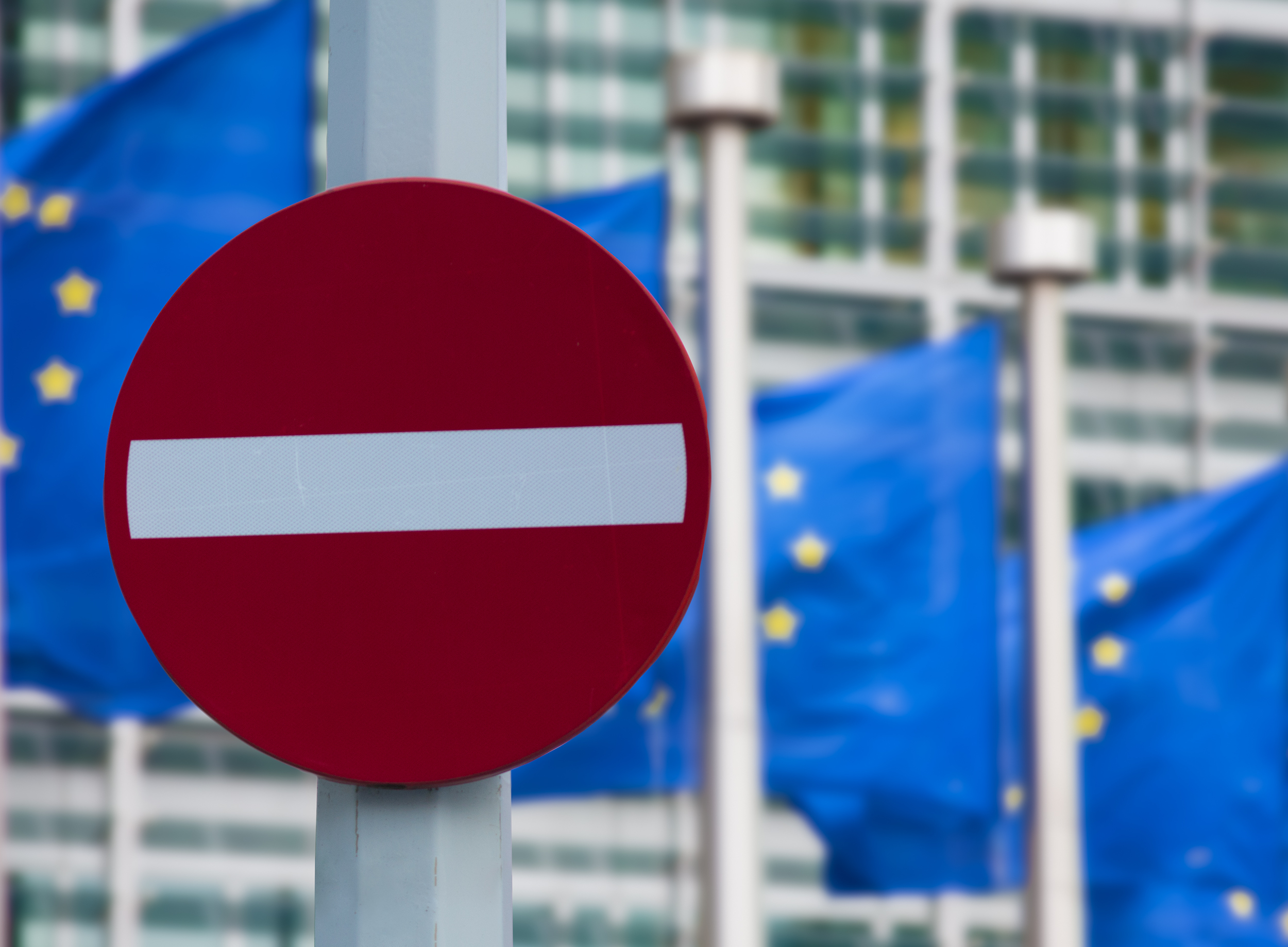 Stop zīme priekšā vairākiem Eiropas Savienības karogiem
